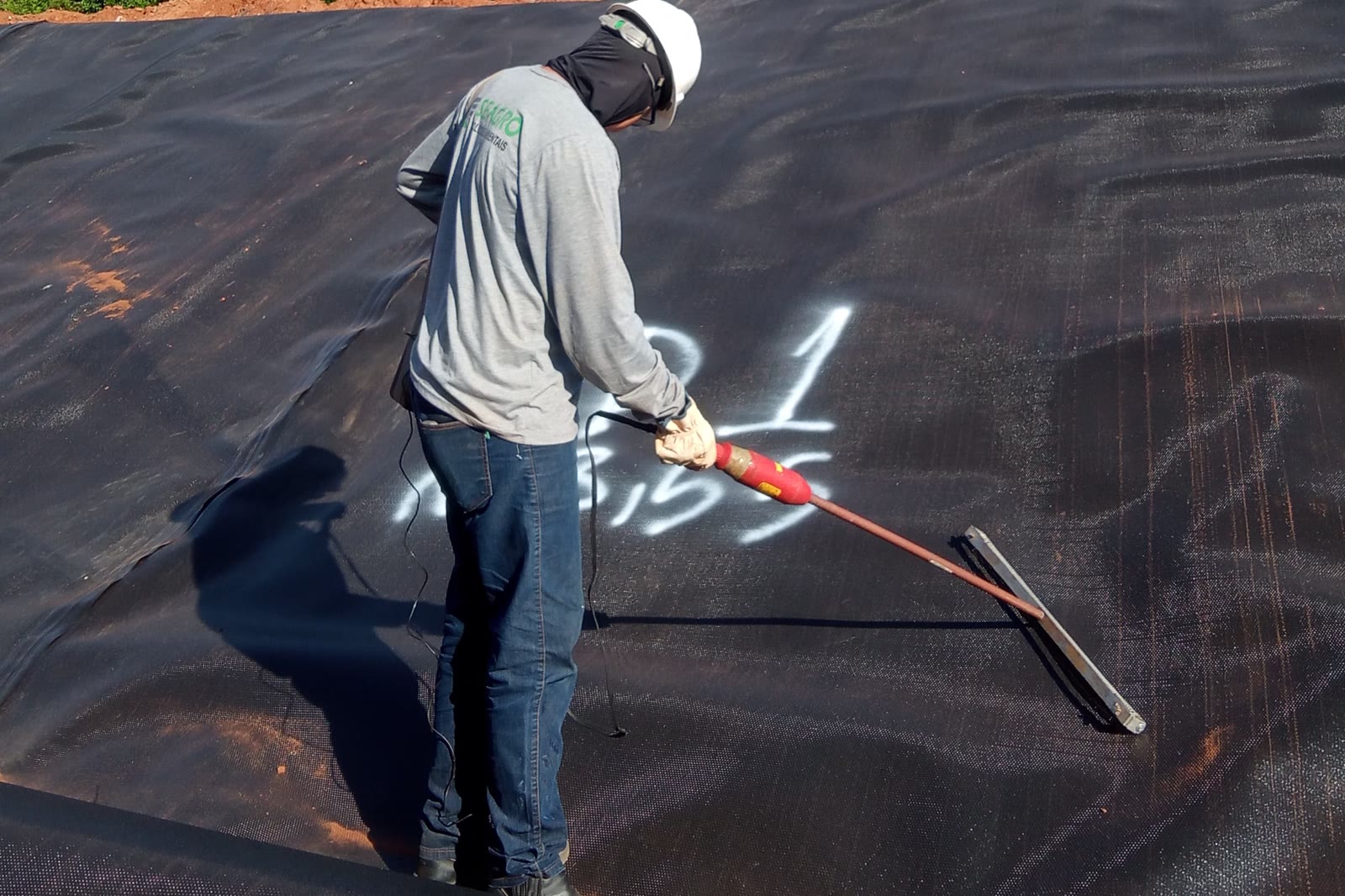 Profissional da SEAGRO inspecionando um painel de geomembrana de PEAD em obra